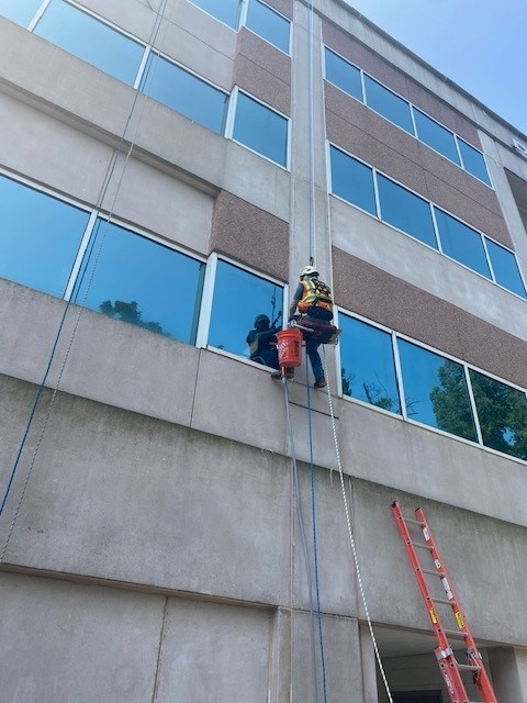 pcm-employee-repairs-building-window-calking-ppe-harness